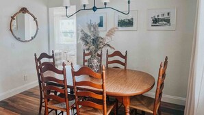 A dining area with a round wooden table surrounded by four wooden chairs, a vase with dried plants, and a chandelier. - 3 Bedroom Modern Vintage in Historic Sanford (Sanford)