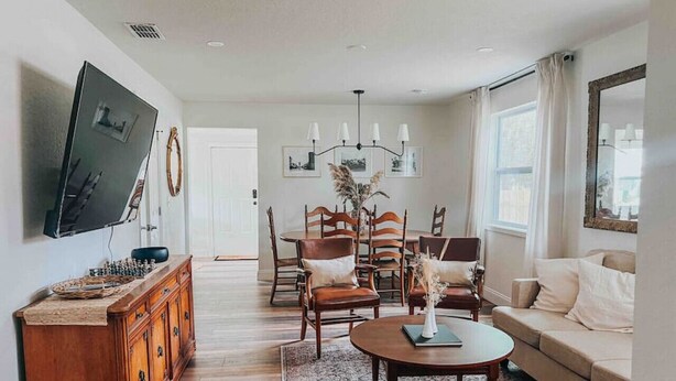 A spacious living room with a wooden coffee table, a sofa, and a television mounted on the wall. - 3 Bedroom Modern Vintage in Historic Sanford (Sanford)