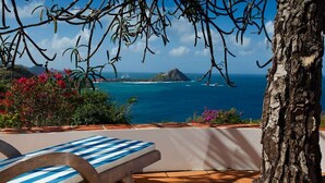 Ein Poolbereich mit Blick auf das Meer und ein Berg.
