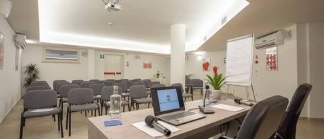 Una sala de conferències amb una taula llarga, cadires, un ordinador portàtil, una pissarra i un projecte.