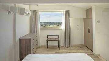 A bedroom with a bed, a desk, a wardrobe, and a window with curtains.