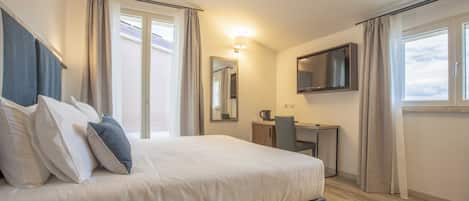Une chambre d’hôtel moderne dotée d’un grand lit, d’un bureau, d’une chaise, d’un téléviseur à écran plat et d’une fenêtre avec des rideaux.