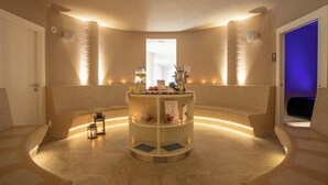 A spa area with a central circular table, benches, and ambient lighting. - Riva Toscana Golf Resort & SPA (Follonica)