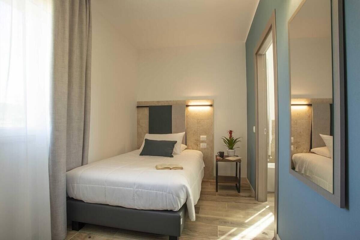 A modern bedroom with a bed, bedside table, and a large mirror.