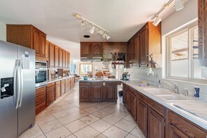 A modern kitchen with wooden cabinets, stainless steel appliances, and a large island. - The Roost: Mesa-Edge Valley Views, Hot Tub & Fenced Dog Orchard near Grand Mesa (Cedaredge)