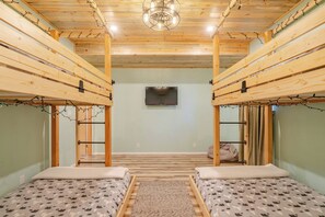 A room with two bunk beds, a ceiling fan, and a television on the wall. - The Roost: Mesa-Edge Valley Views, Hot Tub & Fenced Dog Orchard near Grand Mesa (Cedaredge)