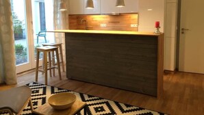 Une cuisine moderne avec un plan de travail en bois, des luminaires suspendus et une vue sur l’extérieur.