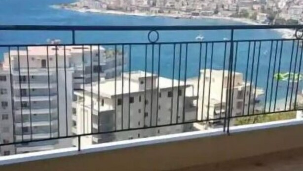 A balcony with a view of a coastal cityscape and the sea.