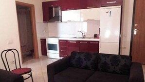 A compact living space with a kitchenette, a sofa, and a chair.