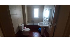 A small bathroom with a toilet, sink, and bathtub. - Family apartment 5 by Hillside apartments TM (Sarande)
