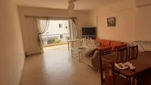 A living room with a sofa, a TV, a dining table, and a balcony. - Family apartment 5 by Hillside apartments TM (Sarande)