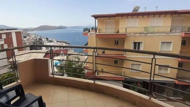 A balcony with a view of the sea and a building with multiple balconies. - Family apartment 5 by Hillside apartments TM (Sarande)