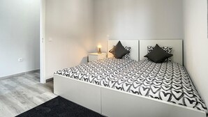 Een moderne slaapkamer met een bed, nachtkastjes en een bijpassend tafeltje.