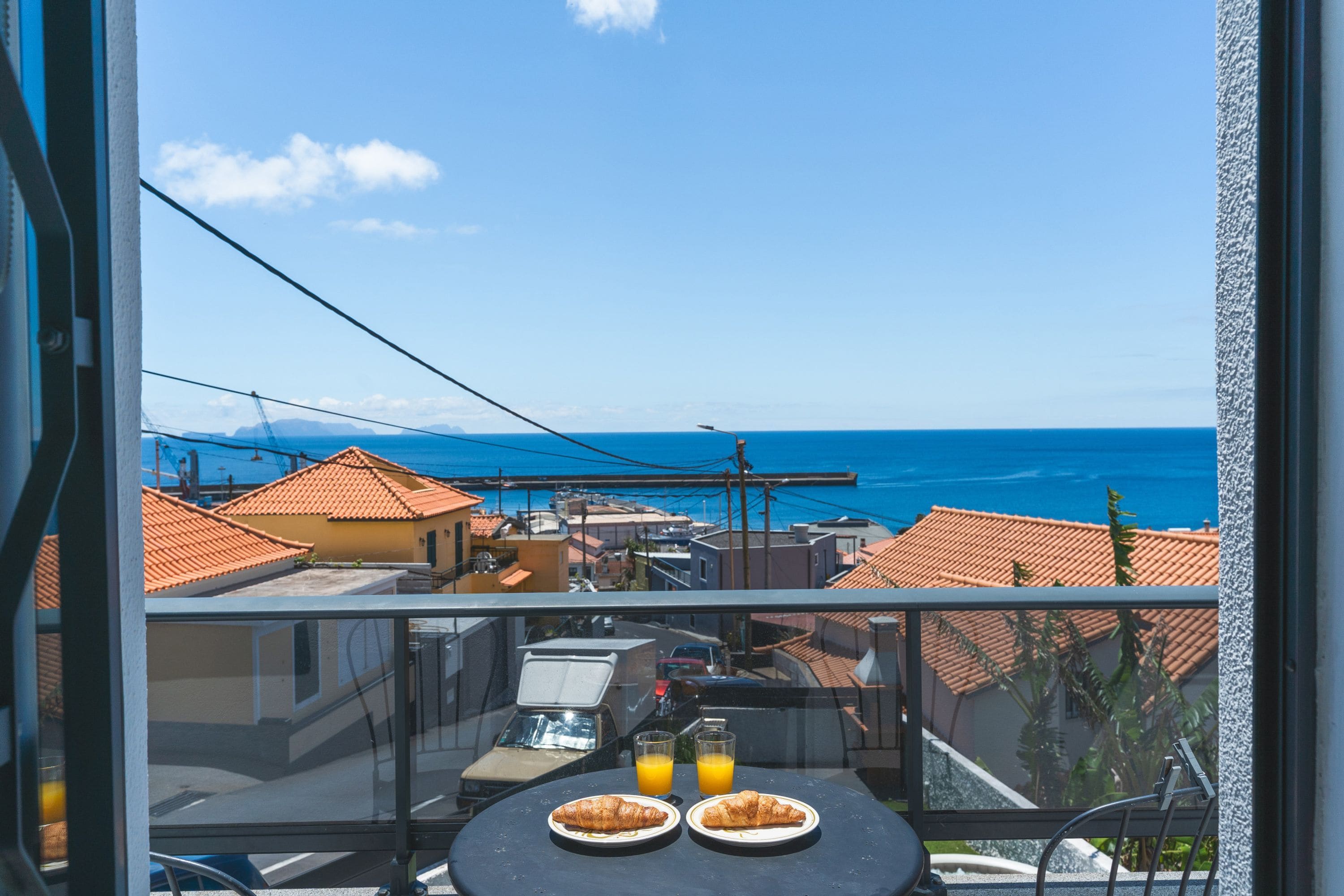 Ein Balkon mit Tisch, zwei Teller Essen und einem Glas Orangensaft.