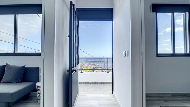 Een modern interieur met een bank, een uitzicht door een glazen deur en een betegelde vloer.