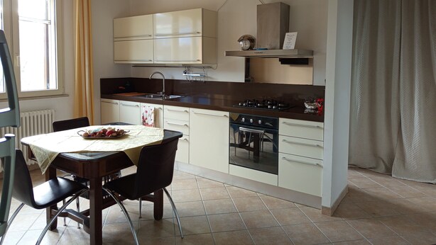 A kitchen with a dining table and chairs, a stove, and cabinets.