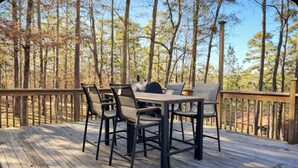 Eine Holzterrasse mit Tisch und Stühlen, umgeben von Bäumen.