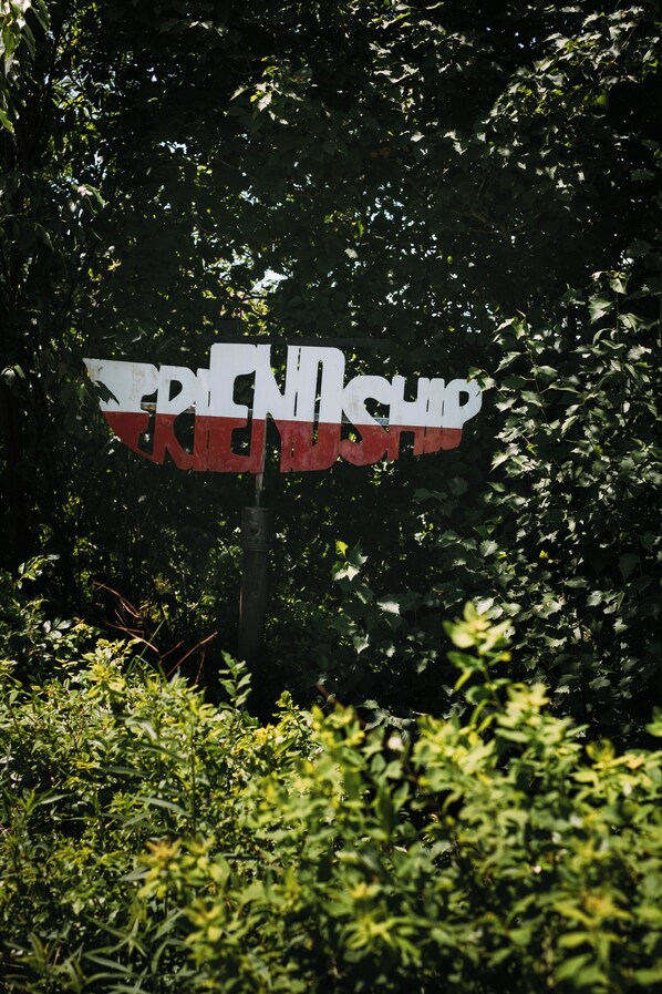 A sign with the text "FRIENDS" in large letters, surrounded by dense foliage. - Rustic-Luxe Escape Near Town w/ Water Access, Kayaks, Games, Fire Pit & Peloton! (Friendship)