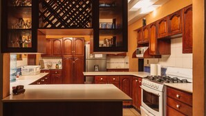 A kitchen with wooden cabinets, a central island, a stove, and a refrigerator.