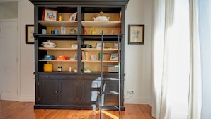 Una librería de madera oscura con varias estanterías, una escalera y diversos objetos decorativos.