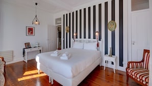 Un dormitorio amplio con una cama grande, una mesita de noche, una silla y un papel tapiz a rayas.