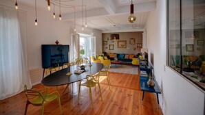 Una sala de estar moderna con comedor, piso de madera y un ventanal grande.