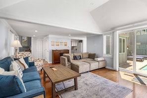 A spacious living area with a sofa, coffee table, and a view of the backyard through large sliding glass doors.