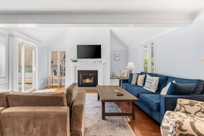 A living room with a fireplace, a television, a blue sofa, and a brown couch.
