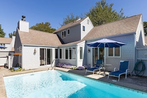 A residential property with a swimming pool, a covered patio, and a garden area.
