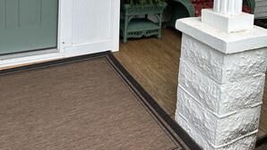 Varanda frontal com porta verde, um pilar branco e o número '622' na porta.