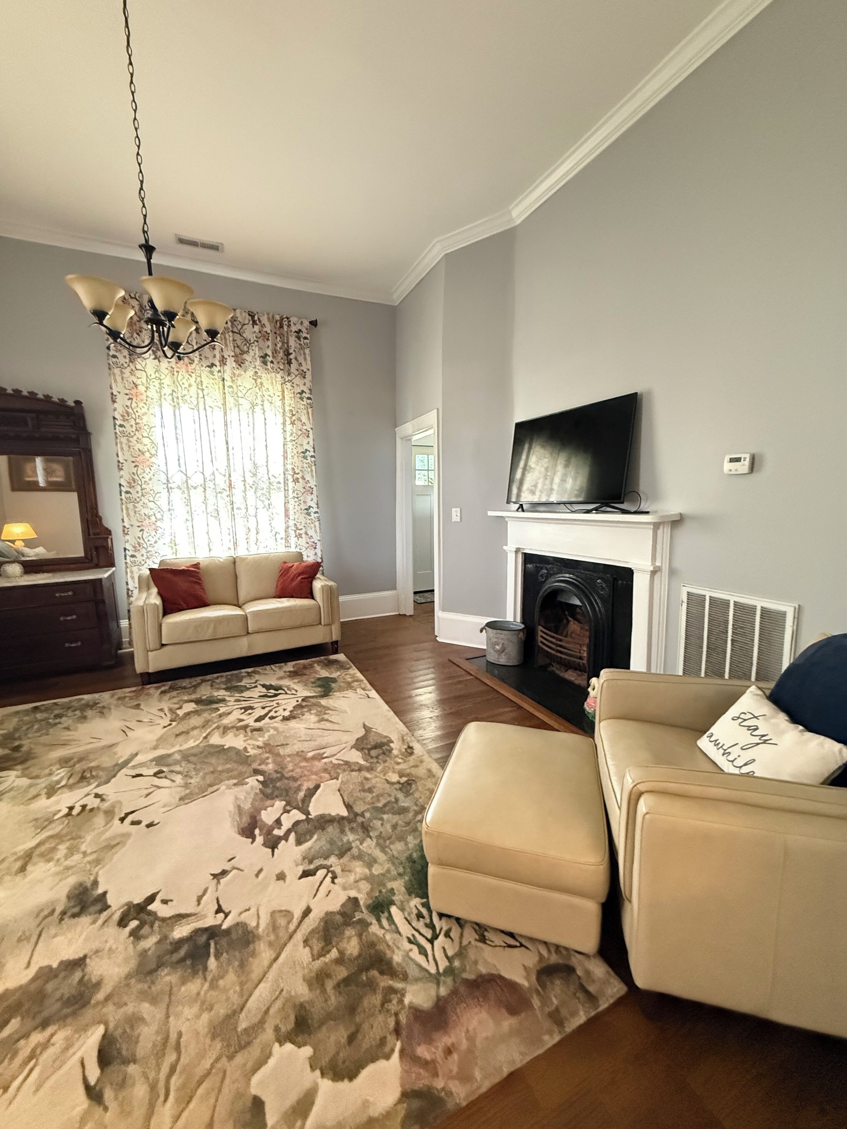 Un salon avec une cheminée, un téléviseur fixé au-dessus, un canapé, une table basse et un tapis à motifs.