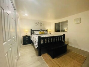 A bedroom with a bed, bedside tables, a bench, a wardrobe, and a window.