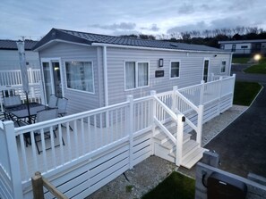 A mobile home with a covered patio, a staircase, and a fenced deck area. - 3 Bedroom Holiday Home in Newquay - Valley Views (Newquay)