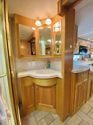 A bathroom with wooden cabinets, a white sink, and a mirror above it. - WELCOME TO THE CITY VIEW RV! (Salem)