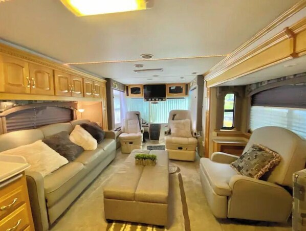 A well-appointed RV interior with a sofa, two chairs, a small table, and a kitchen area. - WELCOME TO THE CITY VIEW RV! (Salem)