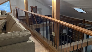 Ein geräumiges Loft mit einer Holztreppe, einem großen Fenster und einer gemütlichen Sitzecke.
