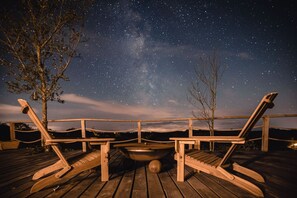 A wooden deck with two lounge chairs and a fire pit under a starry night sky. - Zen Jungle Retreat (Holsworthy)