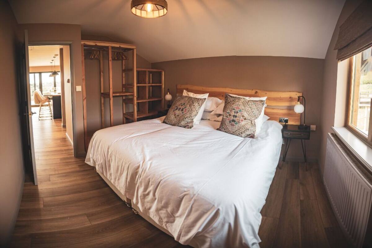 A bedroom with a large bed, wooden headboard, and a walk-in closet.