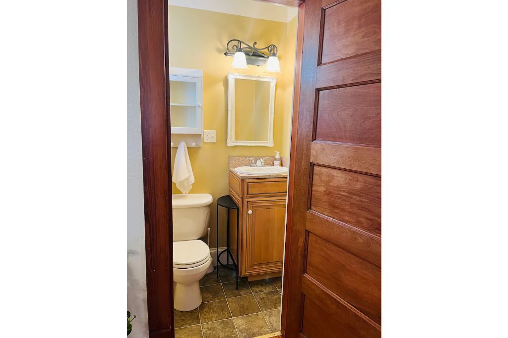 A bathroom with a toilet, sink, and mirror.