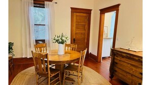 Un comedor con una mesa y sillas de madera, un jarrón con flores y un aparador de madera.