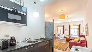 Eine moderne Küche mit Einbauofen, Spüle und Toaster. Ein Essbereich mit einem roten Sofa und einem Tisch mit Blumenvase.