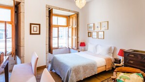 Ein Schlafzimmer mit Bett, Schreibtisch, Stuhl, Kommode und einer Kristallleuchtre.