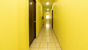 Um corredor comprido e estreito, com paredes amarelas e chão de azulejos.
