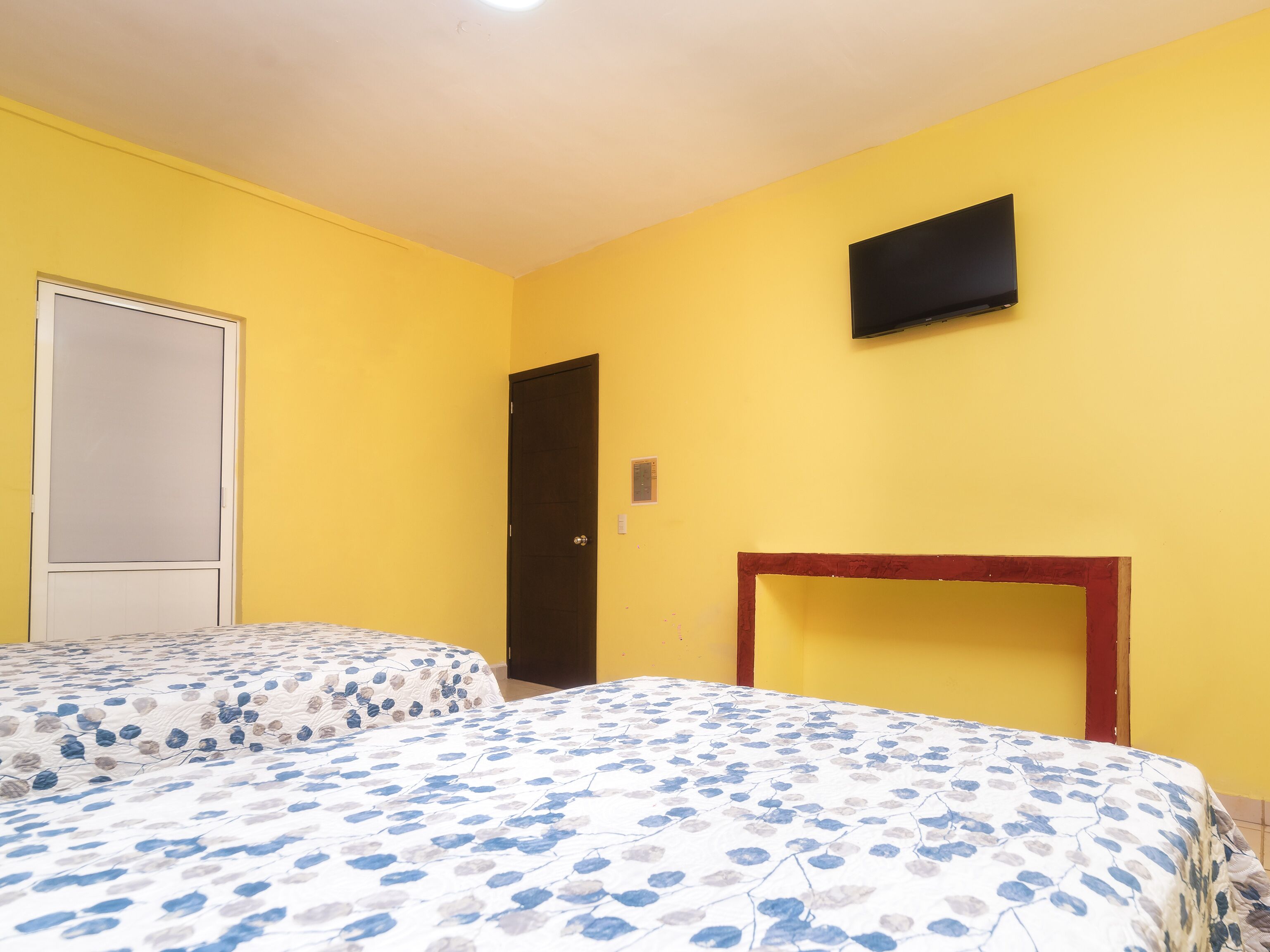 Una habitación con dos camas, televisión y una puerta.