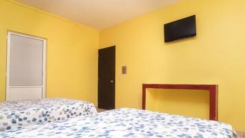Una habitación con dos camas, televisión y una puerta.