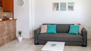 Una sala de estar con un sofá gris, una mesita de centro blanca y una pequeña planta en maceta.