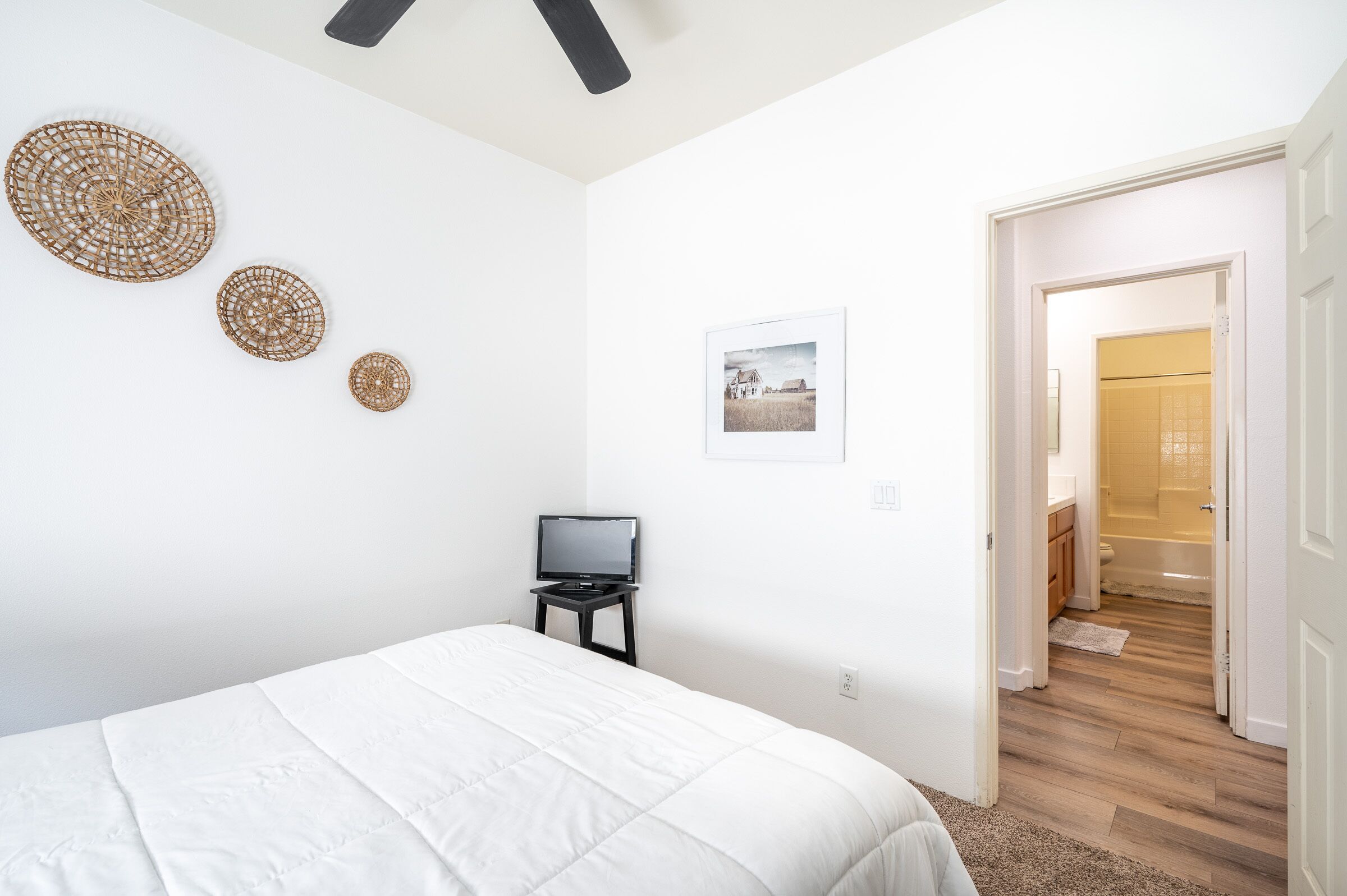 Une chambre à coucher avec un lit, un téléviseur posé sur une petite table et une porte donnant sur une salle de bain.