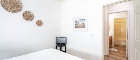Une chambre à coucher avec un lit, un téléviseur posé sur une petite table et une porte donnant sur une salle de bain.