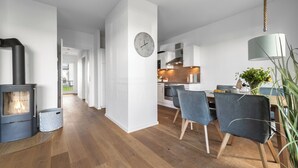 Eine moderne Küche mit weißen Schränken, Holzboden und einem Essbereich mit Stühlen und Tisch.