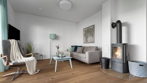 A modern living room with a sofa, armchair, and a wood-burning stove. - "Ocean Blue" sea view vacation apartment on the Baltic Sea - 3 minutes' walk to the beach (Olpenitz)